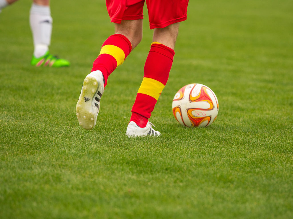 Fußballspieler mit Fußball auf dem Rasen